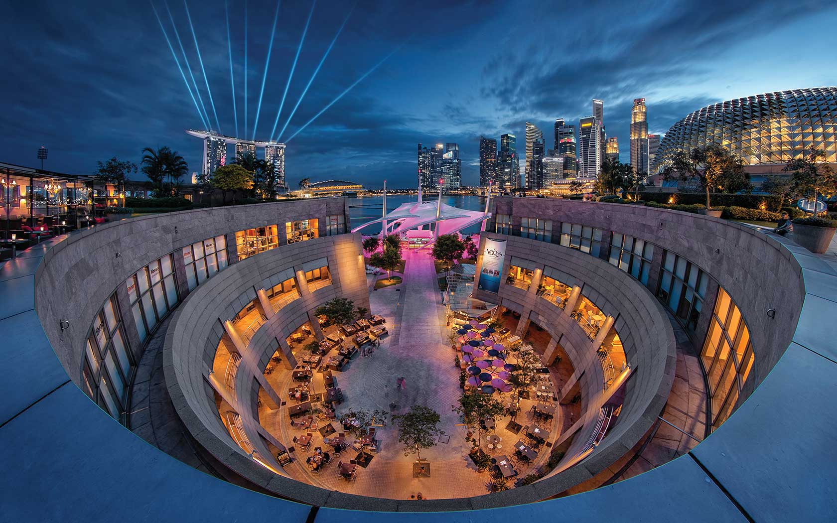 Image of courtyard at Esplanade against the city skyline taken from the Roof Terrace at night.