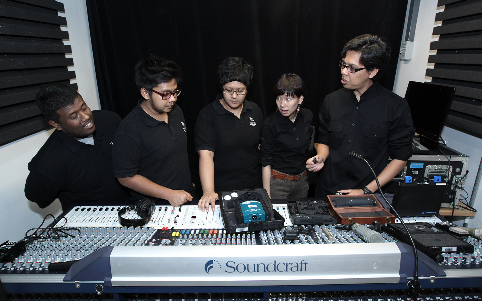 An image of a group of people standing behind a sound console.