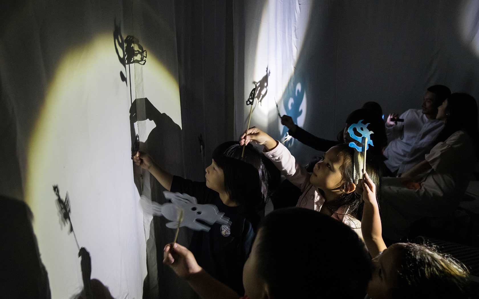 Image of children playing with puppets and shadows during a performance at Esplanade.