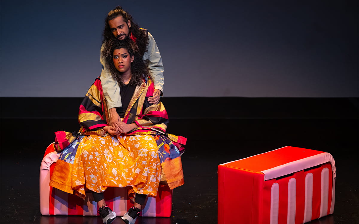 An actress sits with a somber expression while another actor consoles her from behind. A scene from Between 5 Cows and the Deep Blue Sea...